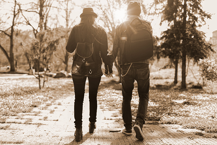 From behind couple holding hand in the park