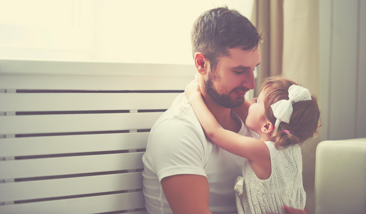 Girl in her fathers arms at home white background